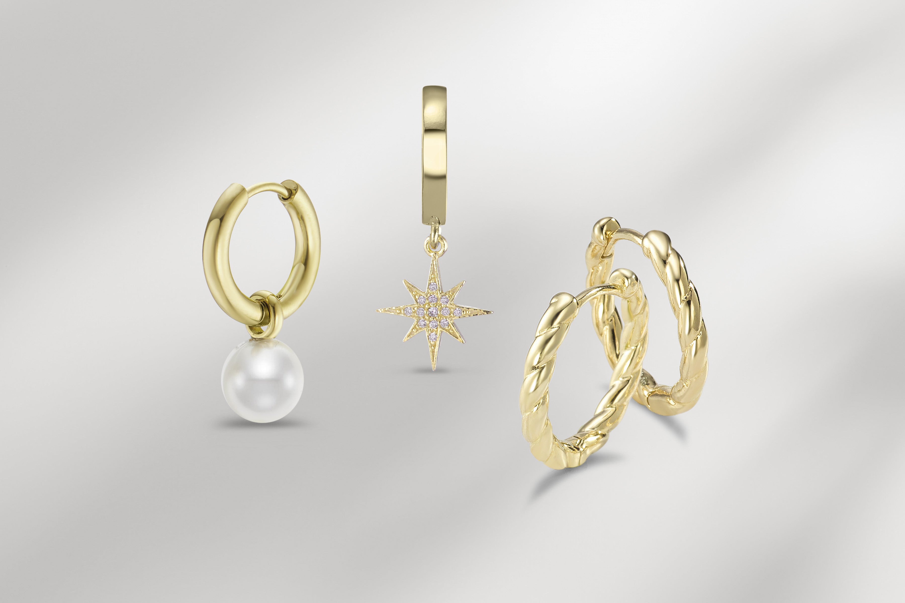 Drei Paar goldene Ohrringe: Creolen mit weißer Perle, Creolen mit Diamant-Stern-Anhänger und gedrehte Creolen